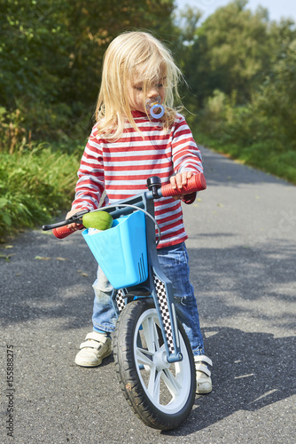 Child riding balance bike. Kid on bicycle in sunny park. Little girl ride glider bike on warm summer day. Preschooler learning to balance on run bicycle. Sport for kids © Petr Bonek