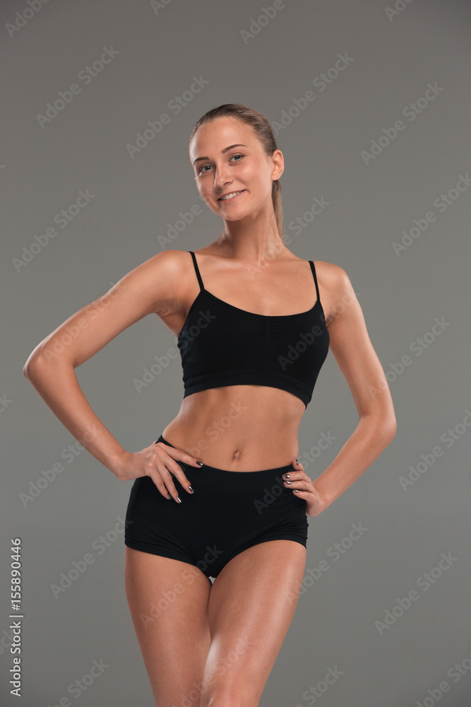Fototapeta premium Muscular young woman athlete on gray