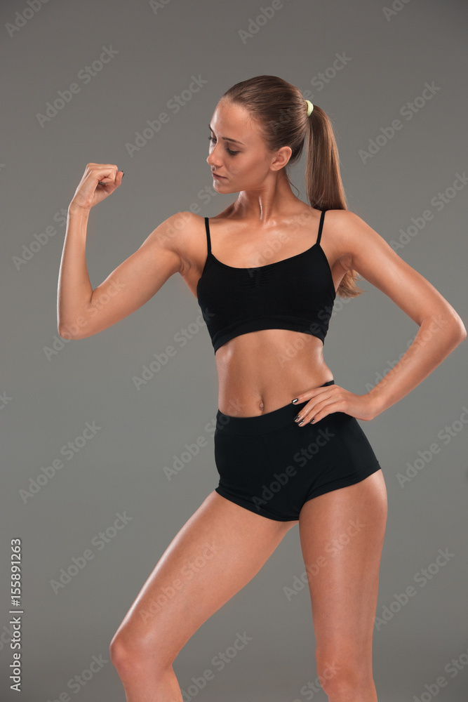 Muscular young woman athlete on gray Muscular young woman athlete on gray