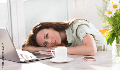 Woman lying over laptop at desk
