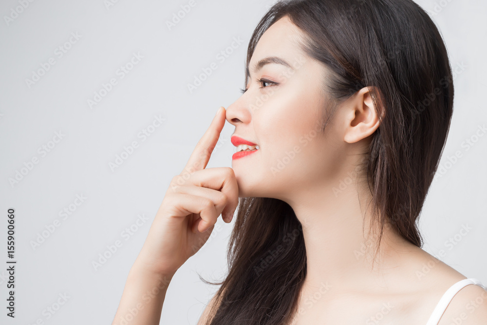 Fototapeta premium Młoda piękna Azjatka z uśmiechniętą buźką i czerwonymi ustami dotyka jej nosa.