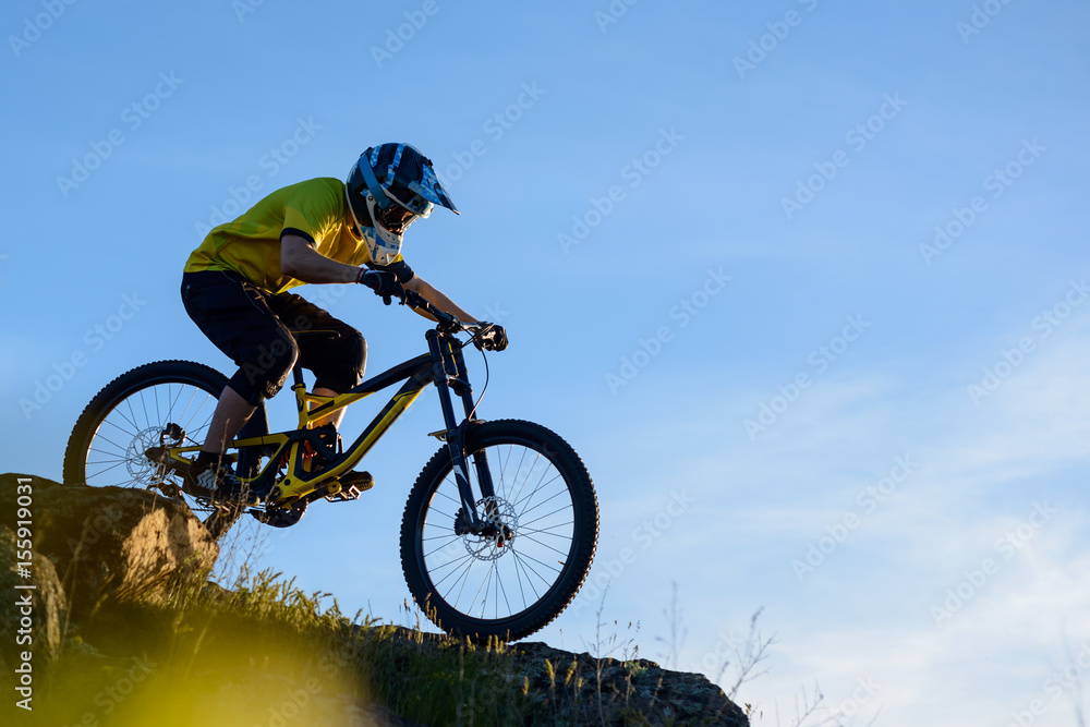 Naklejka premium Cyclist in Yellow T-shirt and Helmet Riding the Mountain Bike Down Rocky Hill. Extreme Sport Concept.
