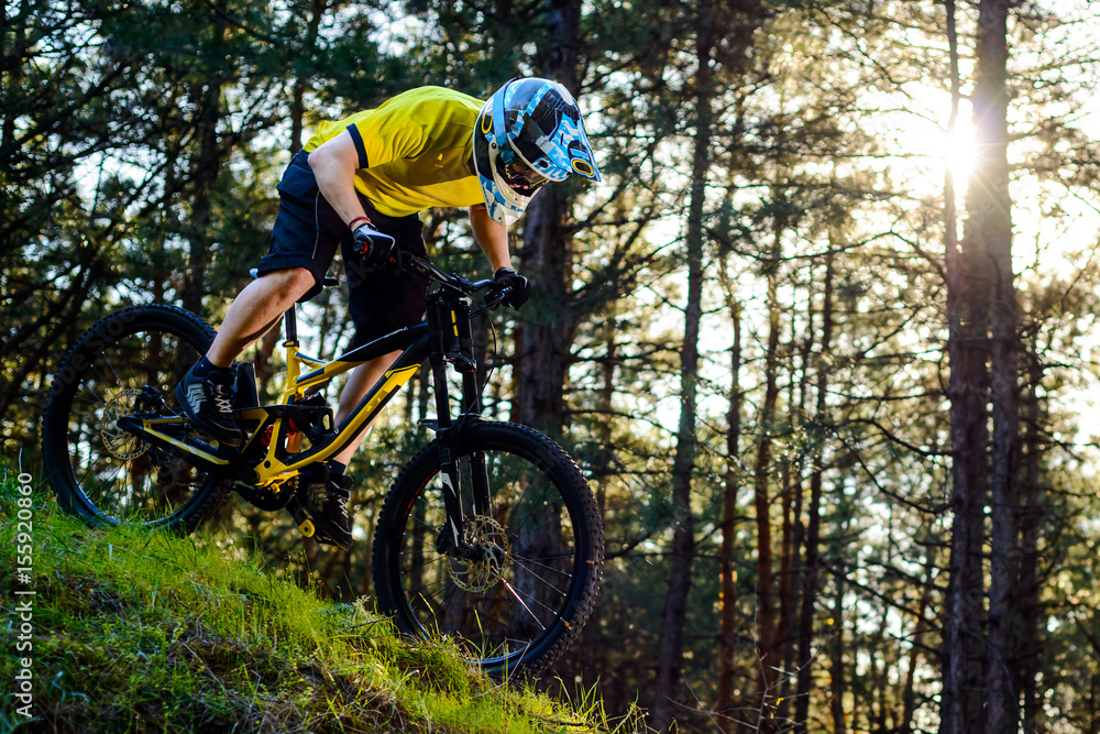Professional Cyclist in Yellow T-shirt and Helmet Riding the Bike Down Hill in Forest. Extreme Sport Concept. Professional Cyclist in Yellow T-shirt and Helmet Riding the Bike Down Hill in Forest. Extreme Sport Concept.