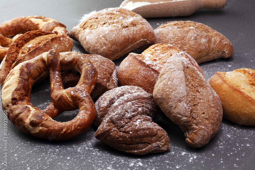 Fototapeta premium Different kinds of bread and bread rolls on board from above. Kitchen or bakery poster design.