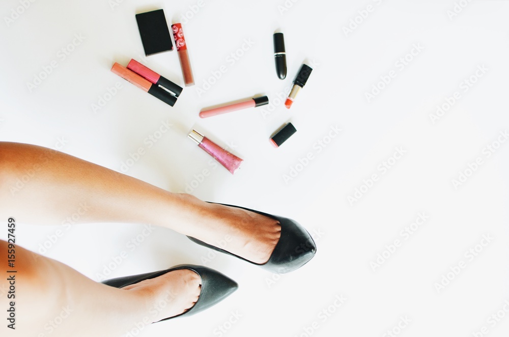 top view woman legs wearing black shoes with cosmetics set on white background. top view woman legs wearing black shoes with cosmetics set on white background.