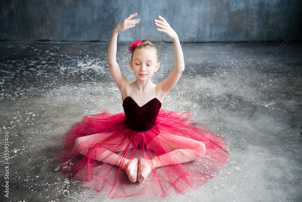 Fototapeta premium little ballerina sitting on floor, raise hands, close eyes