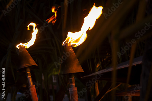 фотографія Iconic torches specific to Hawaii islands burning at night on a summer night