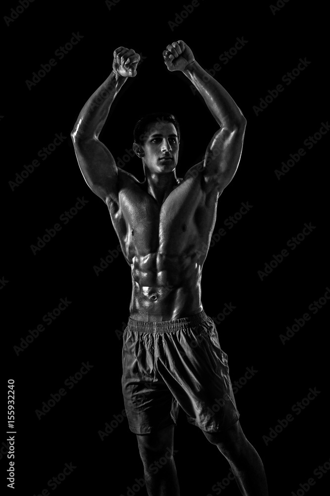 Muscular and fit young bodybuilder fitness male model posing ove