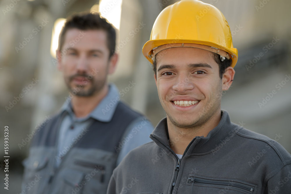smiling builders in hardhats outdoors smiling builders in hardhats outdoors