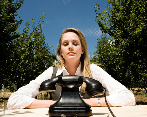 Woman sitting at desk with old telephone photo