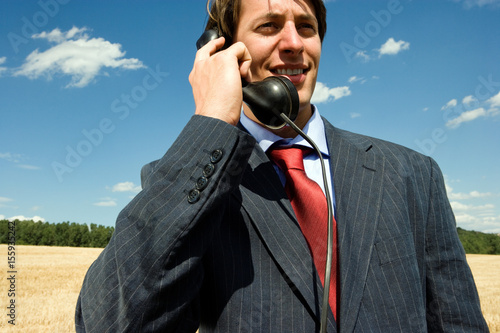 Man on old phone in wheat field. photo