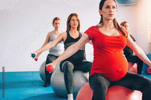 Group of pregnant women exercising and lifting weights feeling strong