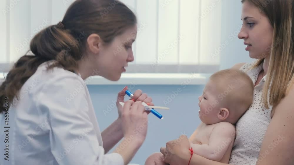 The doctor looks inside the mouth of little baby The doctor looks inside the mouth of little baby