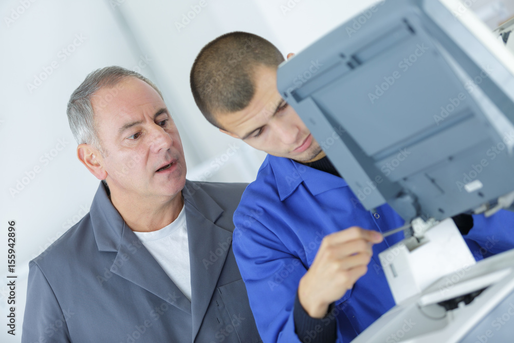 Supervisor watching young technician at work Supervisor watching young technician at work