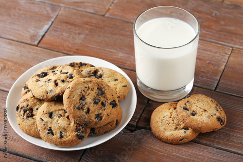 Chocolate chip cookies with glass of milk on brown wooden table