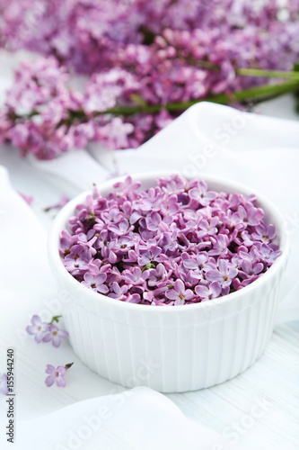 Lilac flowers in bowl on white cloth