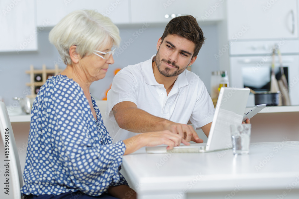 Young man showing elderly lady how to use laptop Young man showing elderly lady how to use laptop