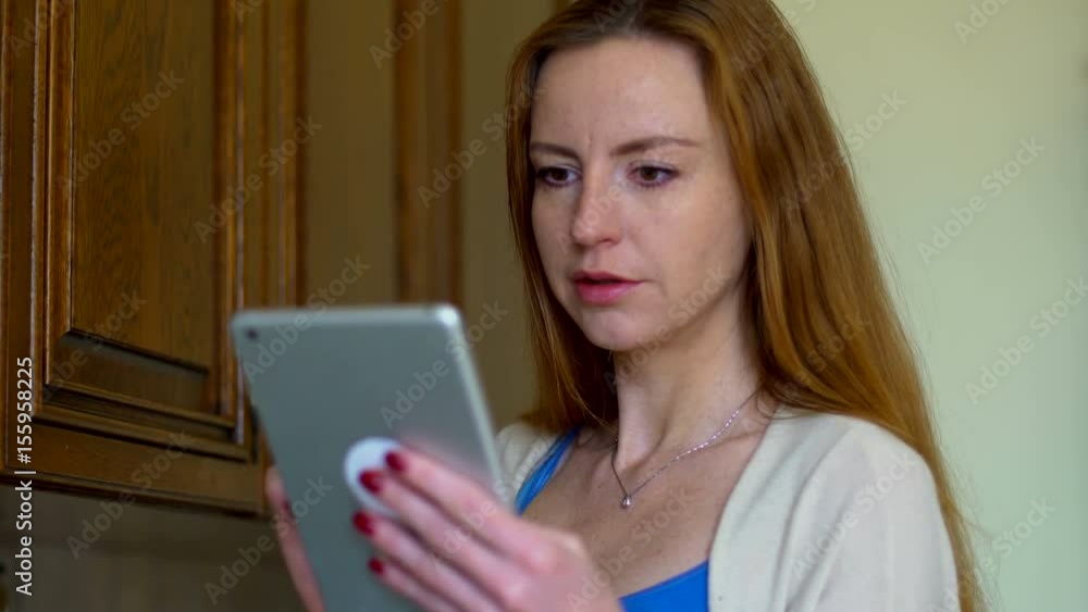 Woman uses a tablet in the kitchen. Technology and internet concept. Dolly shot Woman uses a tablet in the kitchen. Technology and internet concept. Dolly shot