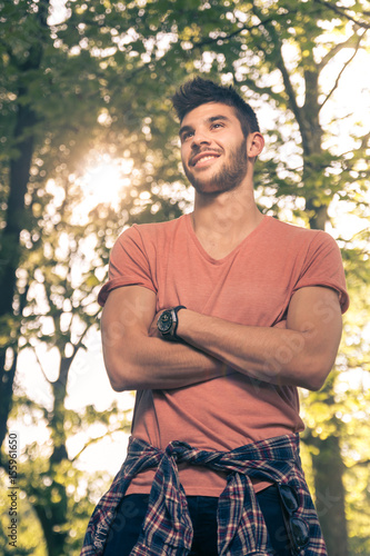 one young man, smiling, upper body shot, outdoors nature sunny