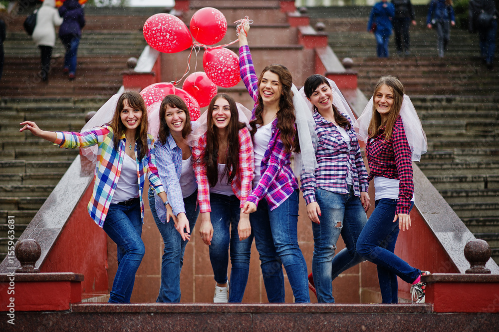 Obraz premium Group of six girls having fun at hen party, with balloons under rain at stairs of city.