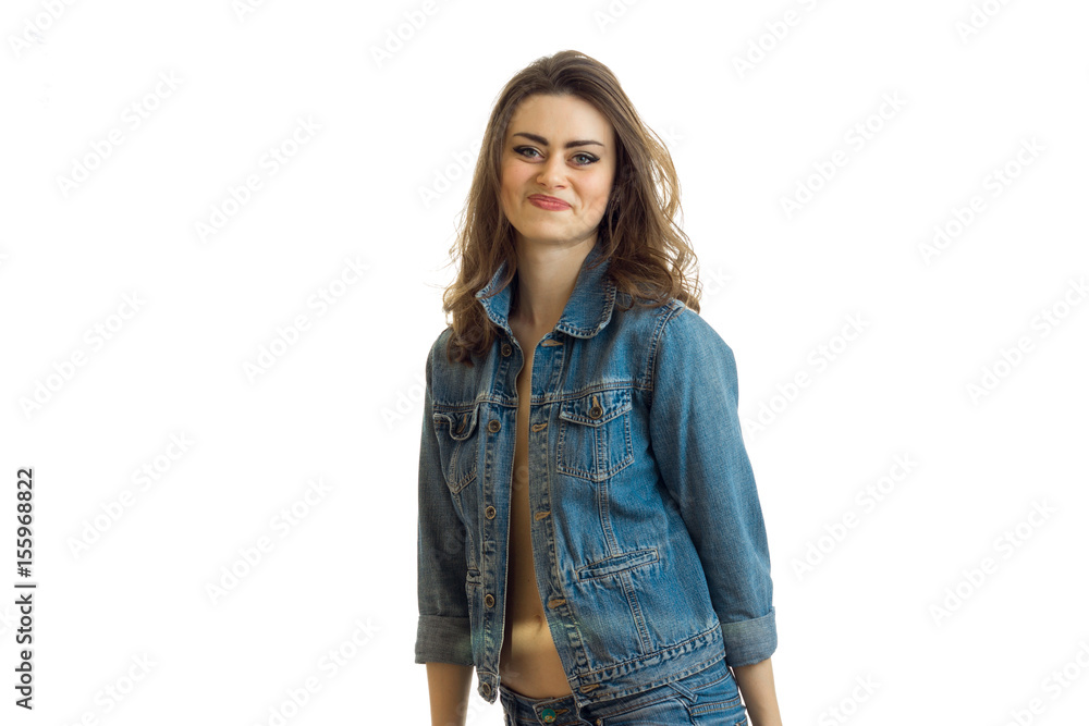 smiling beautiful brunette stands in jeans jacket and looks into a camera smiling beautiful brunette stands in jeans jacket and looks into a camera