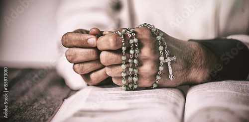 Woman hands praying with rosary and bible