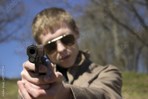 A young man with a gun in a field of dry grass