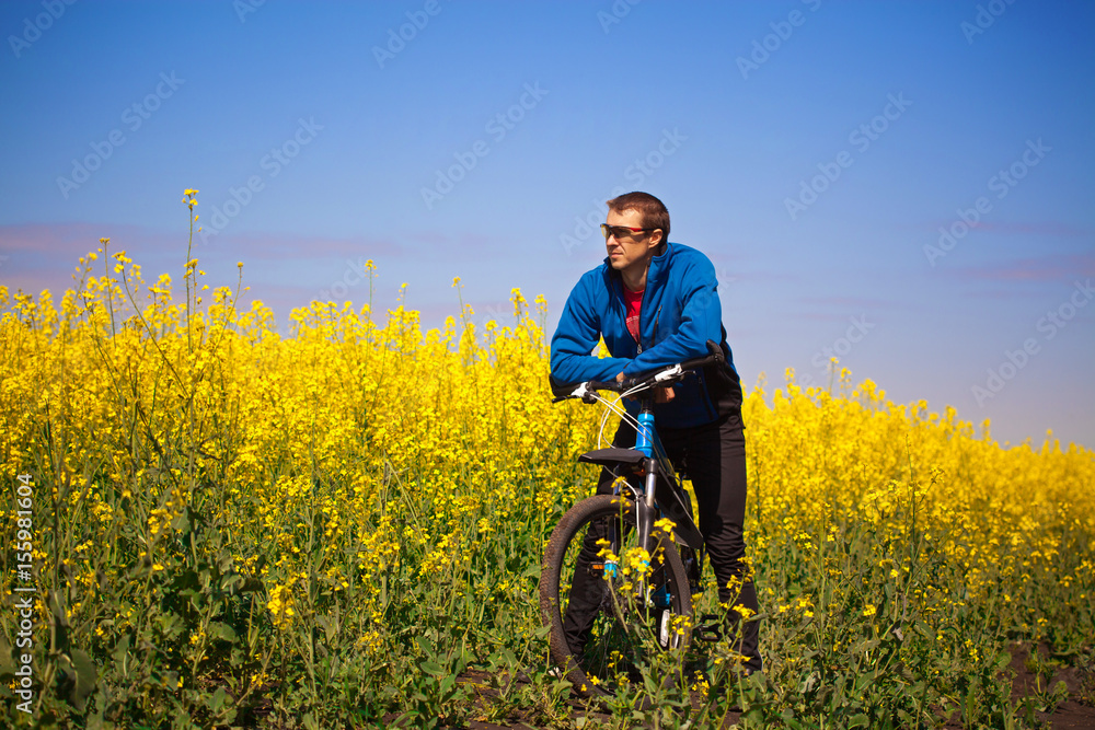 Young bicyclist rides in rapeseed field