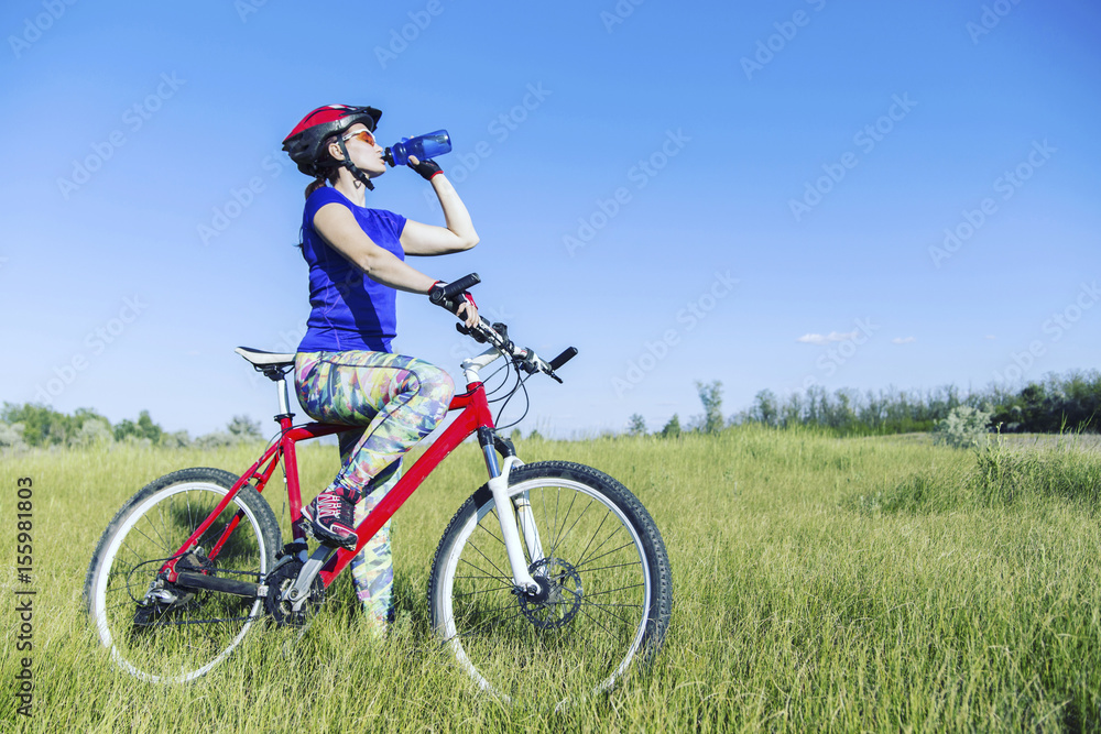 Attractive, healthy woman drinks from her water bottle on mountain bike. active outdoor lifestyle concept.