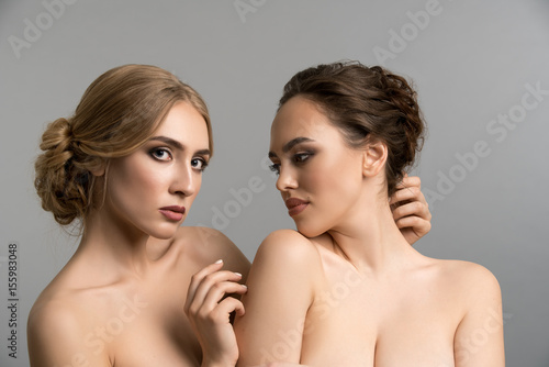 Two models topless posing together in studio