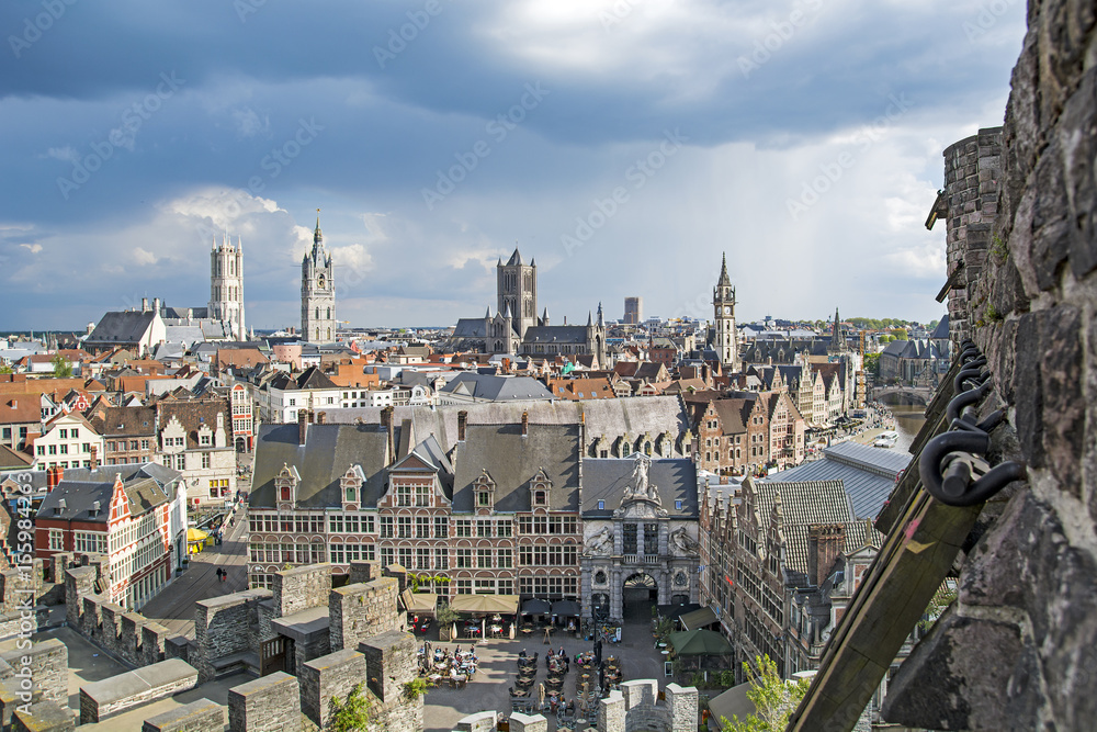 Cityscape in old town Gent of Belgium, belfry and St Bavo cathedral view through arrowslit from Gravensteen castle