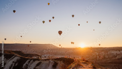 Colorful air balloons flying over Cappadocia landscape at sunrise