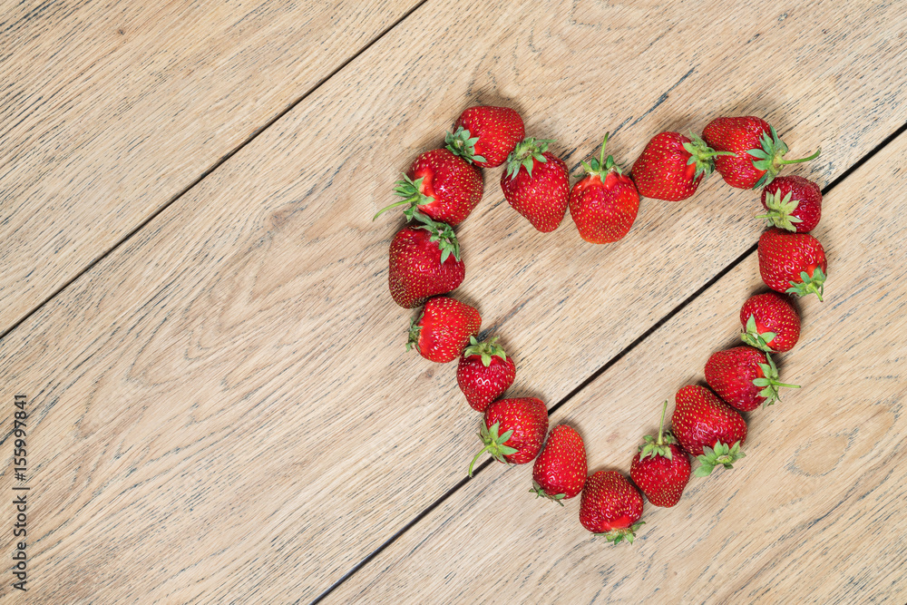 Ripe strawberries laid out on an old wooden table in the shape of a heart Ripe strawberries laid out on an old wooden table in the shape of a heart