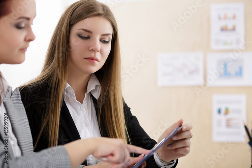 Two woman sitting at office and looking at charts