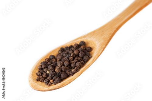 Black pepper in wooden spoon isolated on white