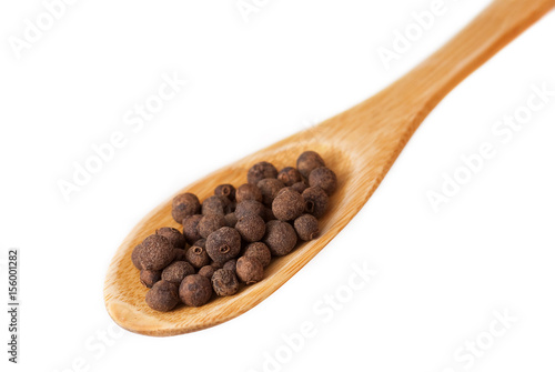 Allspice in wooden spoon isolated on white