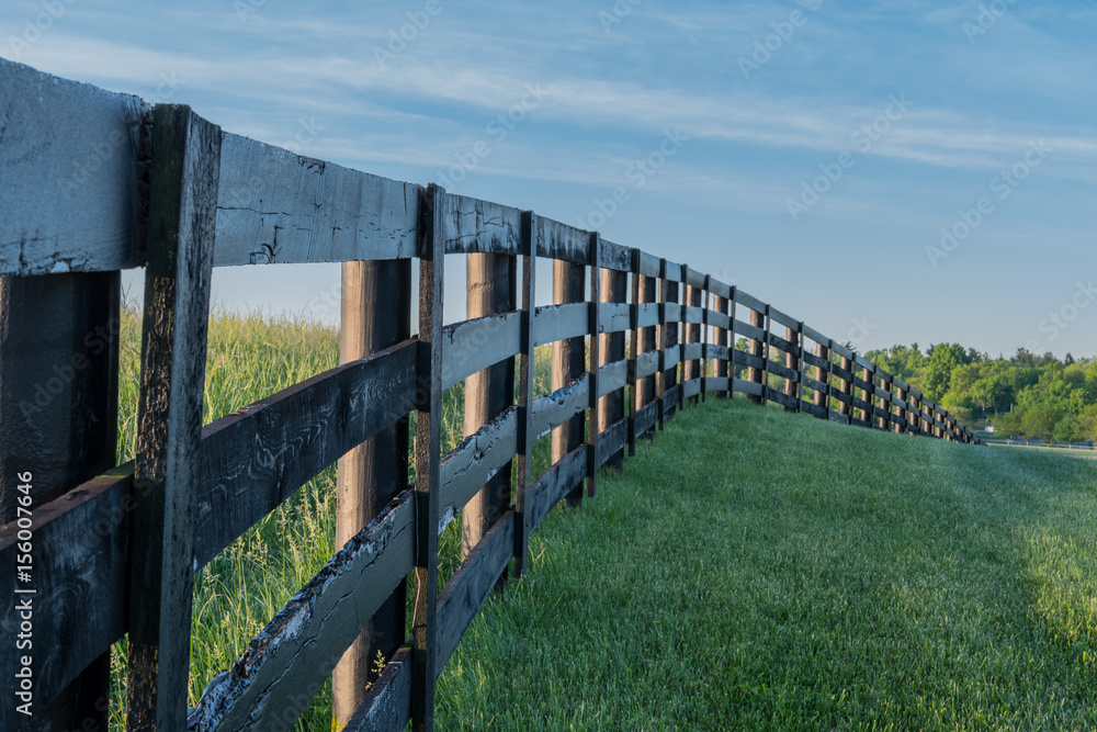 Obraz premium Grassy Hill Cut by Black Fence