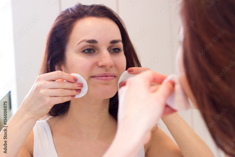 Young woman removing makeup in bathroom