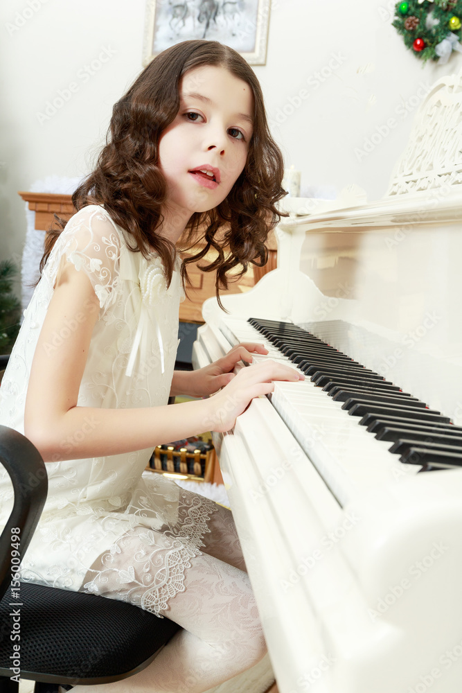Beautiful girl in a white dress sitting at the piano. Beautiful girl in a white dress sitting at the piano.