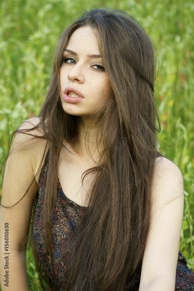 Naklejka premium portrait of young beautiful girl sitting on grass
