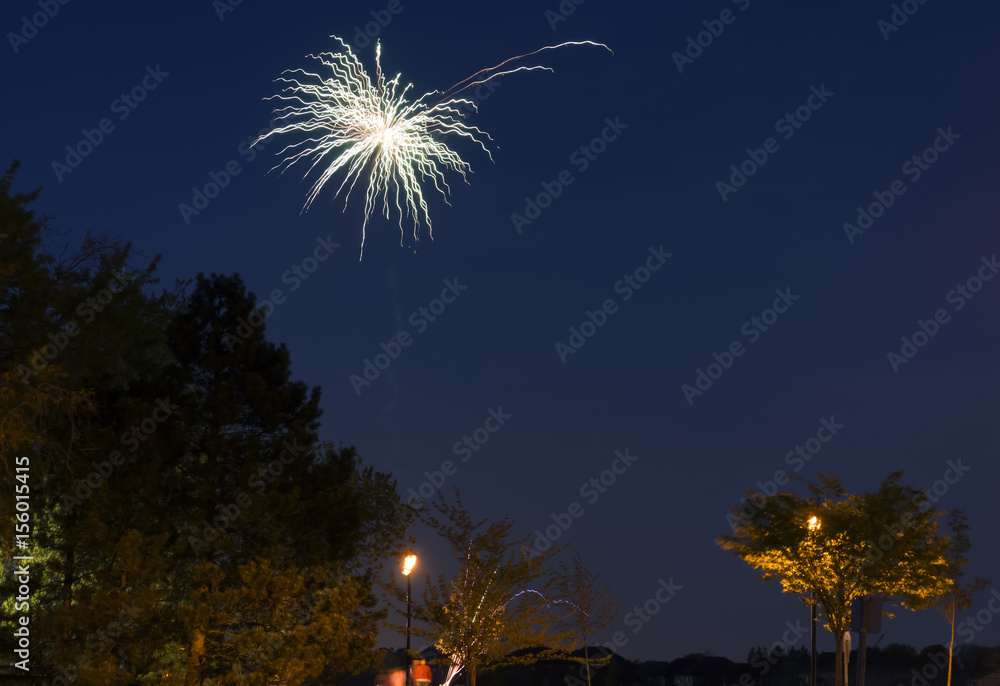 Fireworks bursting high in the sky above watchers at a community park Fireworks bursting high in the sky above watchers at a community park