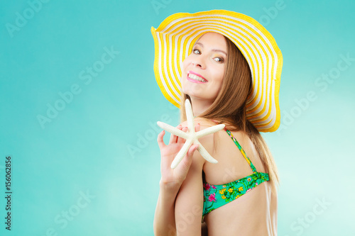 Woman in yellow hat holding white shell
