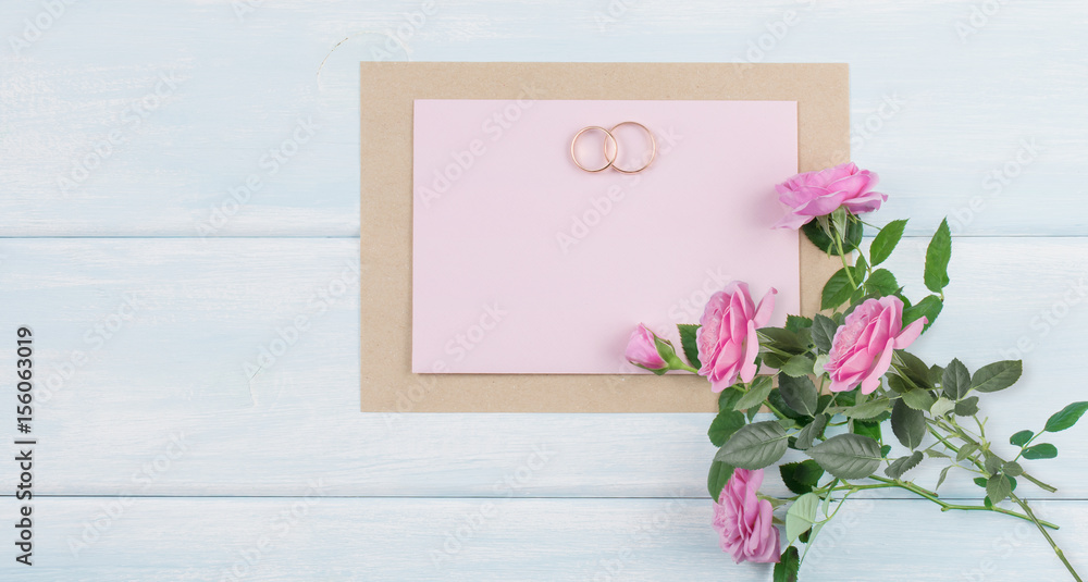 Pink roses and bridal rings with paper greeting card for wedding on background of shabby wooden planks. Pink roses and bridal rings with paper greeting card for wedding on background of shabby wooden planks.