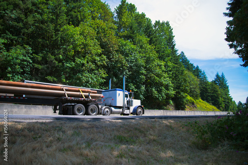Wallpaper Mural Big Rig semi truck driving highway carry long pipes on flat bed trailer Torontodigital.ca