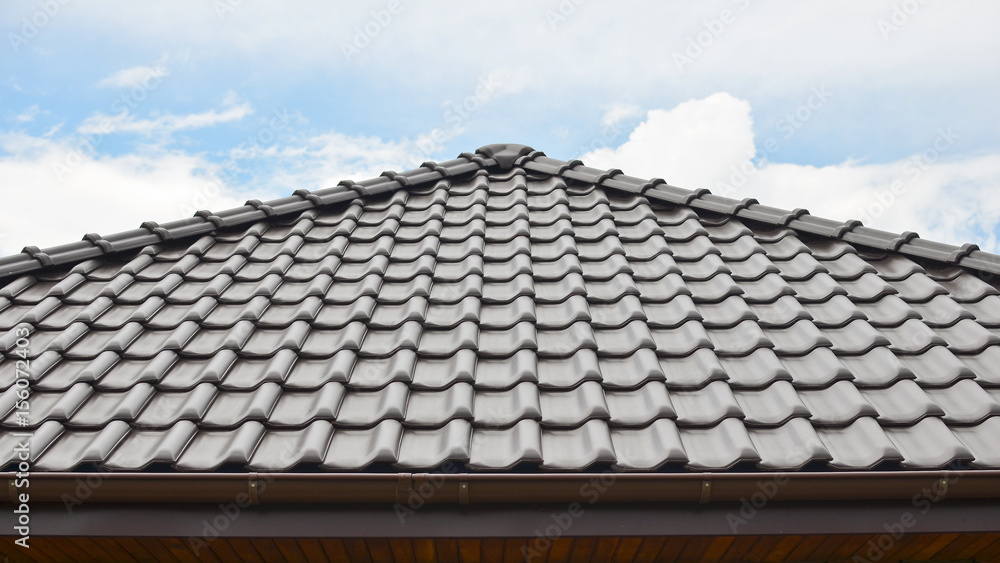 Dark brown ceramic tile roof against blue sky. Dark brown ceramic tile roof against blue sky.