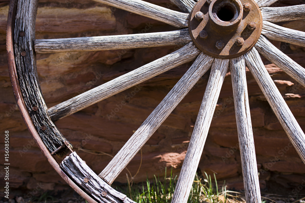 Fragment of the old wheel near a stone wall Fragment of the old wheel near a stone wall