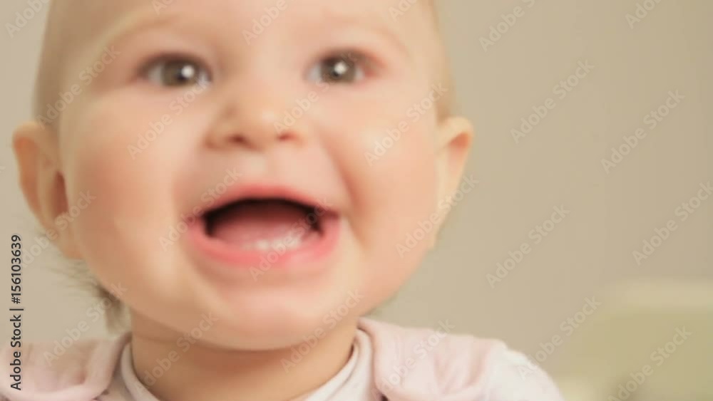 Little girl at the age of one year, carefully and emotionally looking at the mother up-close and laughing, standing in a cot Little girl at the age of one year, carefully and emotionally looking at the mother up-close and laughing, standing in a cot