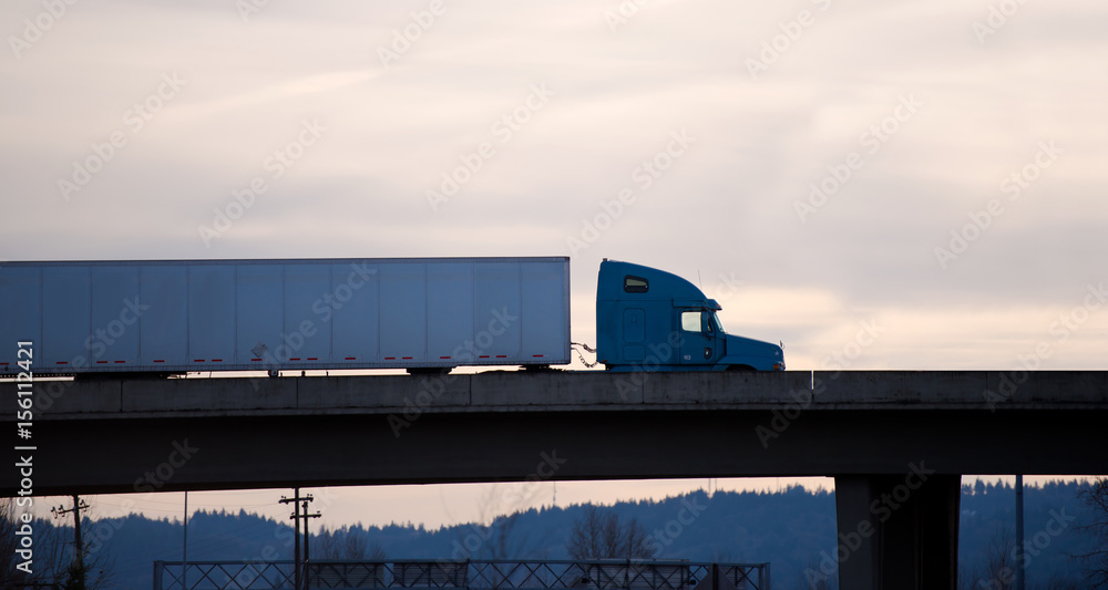 Obraz premium Modern semi truck trailer on overpass bridge evening silhouette