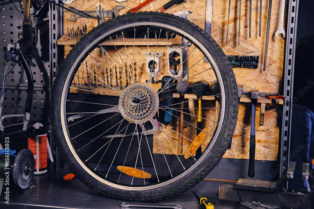 Mountain bike wheel over service tool stand in a workshop.