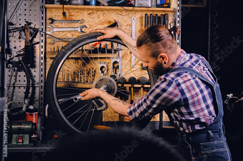 Fototapeta Naklejka Na Ścianę i Meble -  Mechanic removing bicycle rear cassette in a workshop.